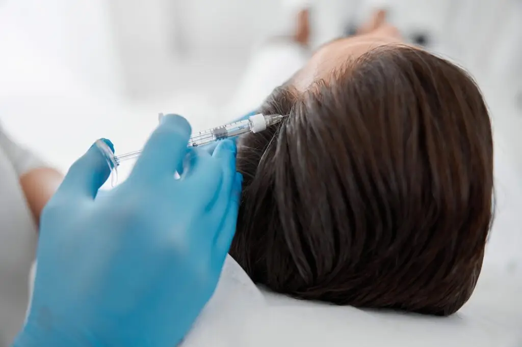 Specialist does injection in patient head skin during meso therapy procedure in cosmetology clinic